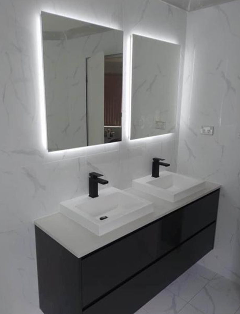 Bathroom renovation with backlit mirrors, twin white basins and a dark wall-hung vanity