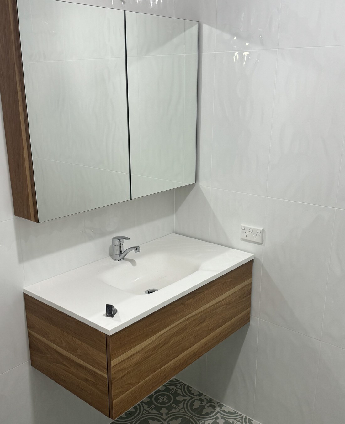 Completed A2Z bathroom with a timber wall-hung vanity, a mirrored cabinet, white gloss wall tiles and patterned green floor tiles